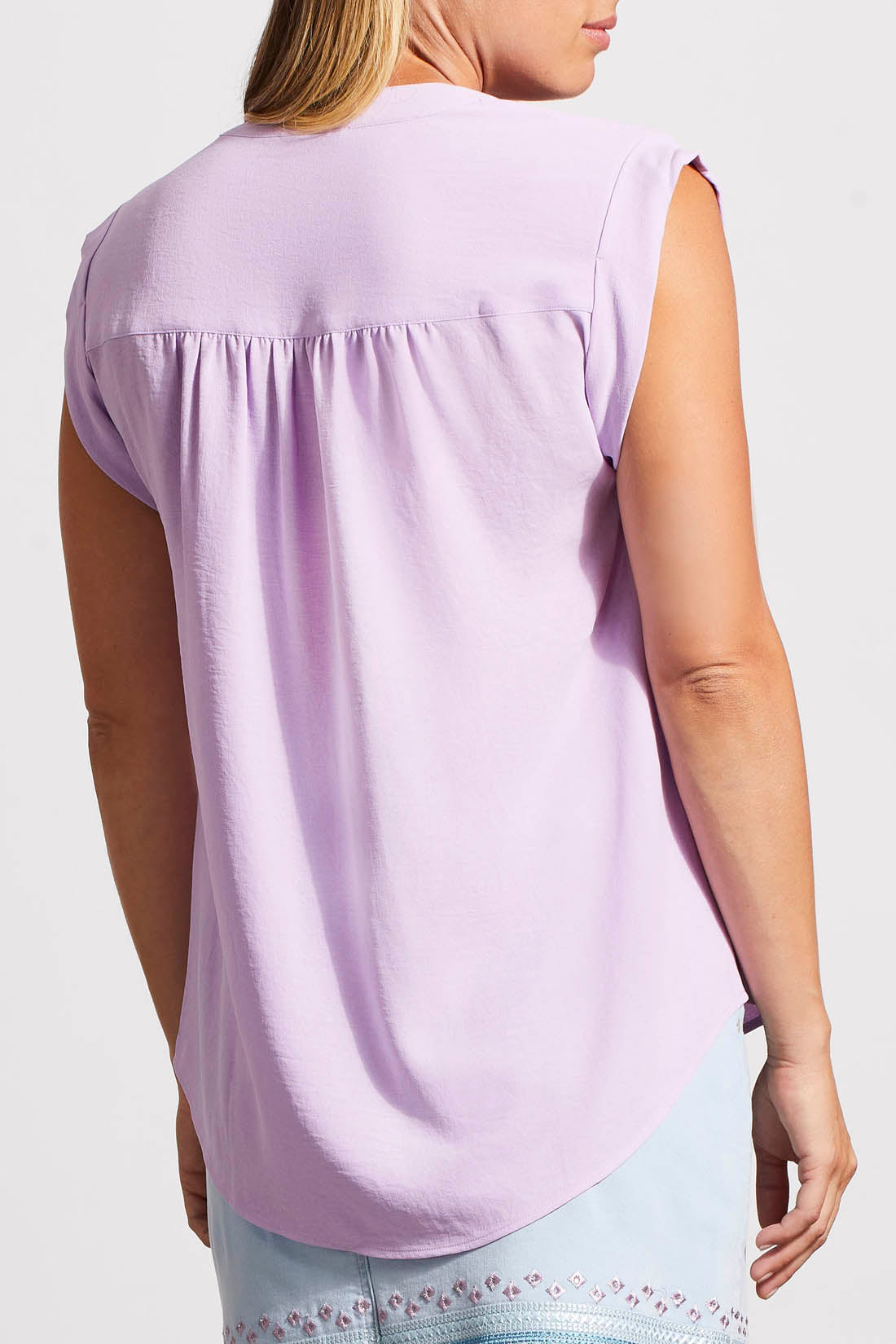 Woman wearing a stylish, light purple Tribal cap sleeve blouse with frill details around the v-neckline.