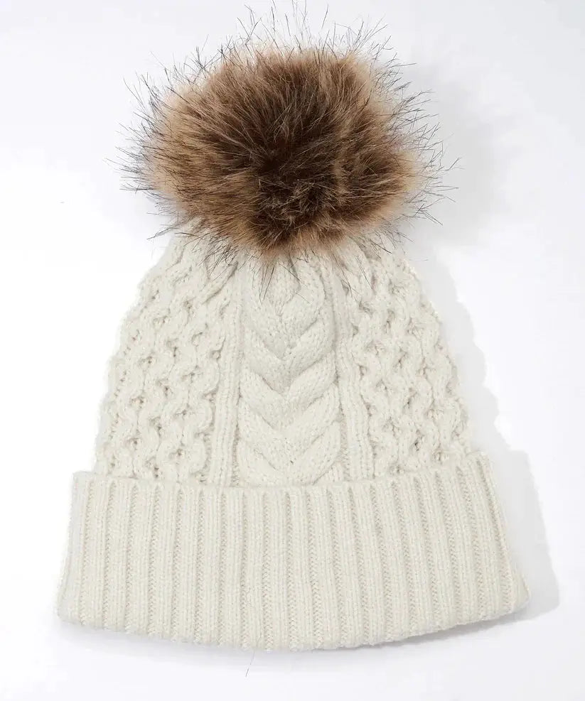 A woman wearing an Echo New York Recycled Wishbone Cable Pom Hat.