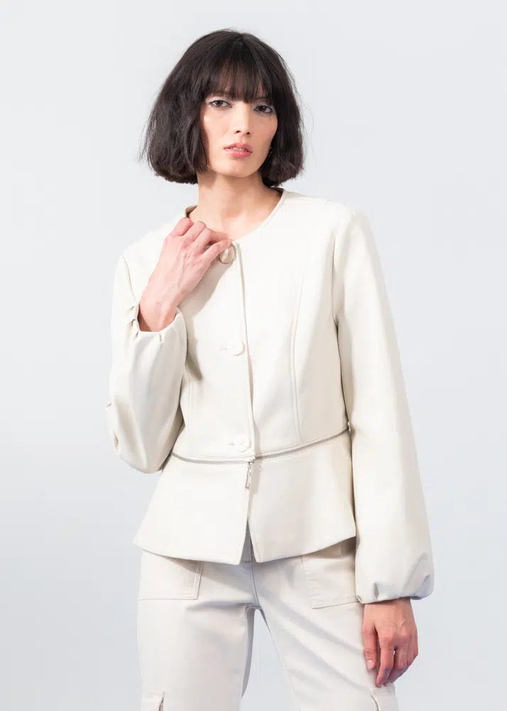 A person with short dark hair models a chic ensemble featuring Elena Wang's Detachable Zip Up Jacket in cream, paired with matching wide-legged trousers. The black top and pointed shoes provide contrasting elegance to complete this stylish look against a simple backdrop.