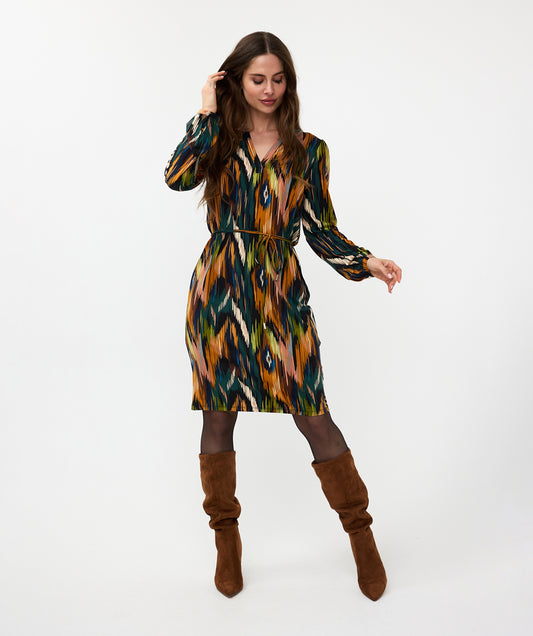 Wearing the versatile and stylish V-Neck Amazon Dress by Esqualo, this person pairs the vibrant, multicolored patterned garment with classic brown boots against a clean white background.