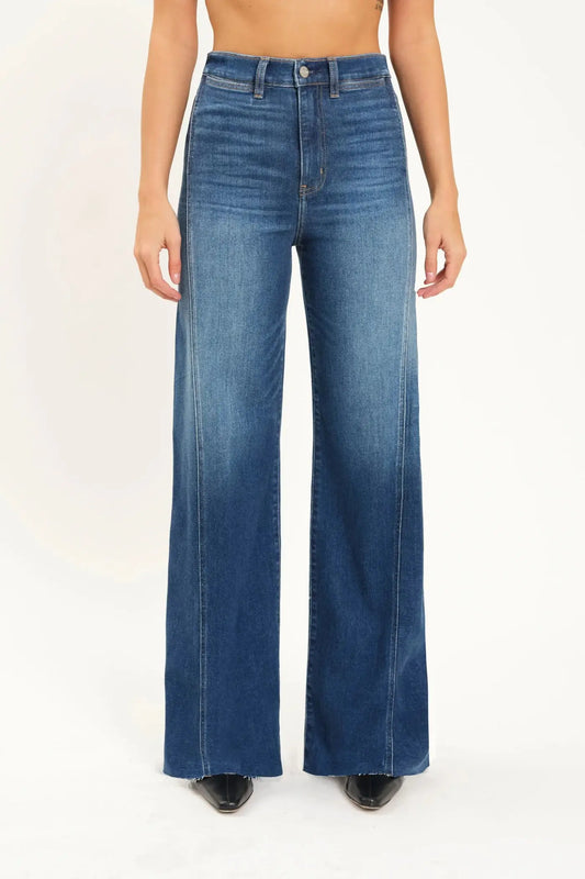 A person wearing Daze's Far Out With Front Seam High Rise wide-leg blue jeans stands facing forward against a plain background.