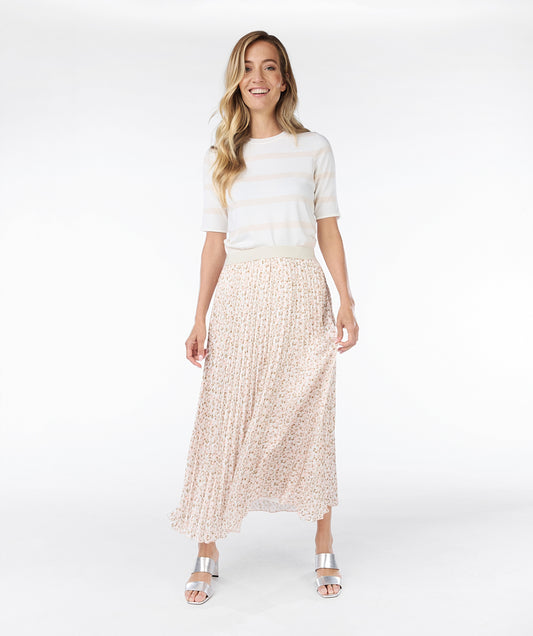 A person is wearing a white top, an Esqualo Pastel Skirt featuring a small floral pattern that offers a flattering fit, and white heeled sandals. The image showcases the stylish look from the back view of the outfit.