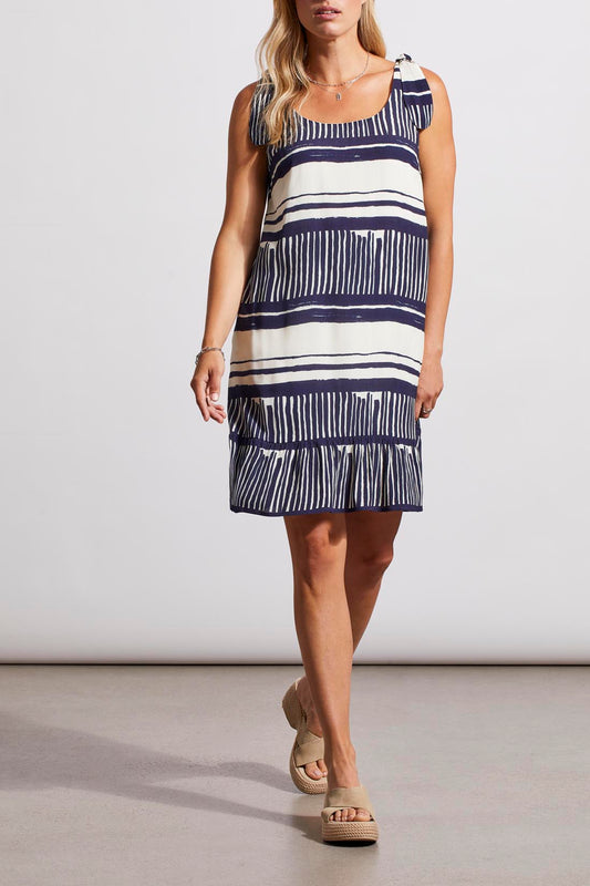 A person wearing a fashion-forward, Tribal sleeveless dress with lining and platform sandals stands against a neutral background.