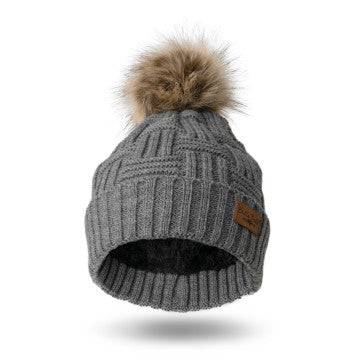 A woman wearing a Britt's Knits Classic Pom Hat in cold weather.