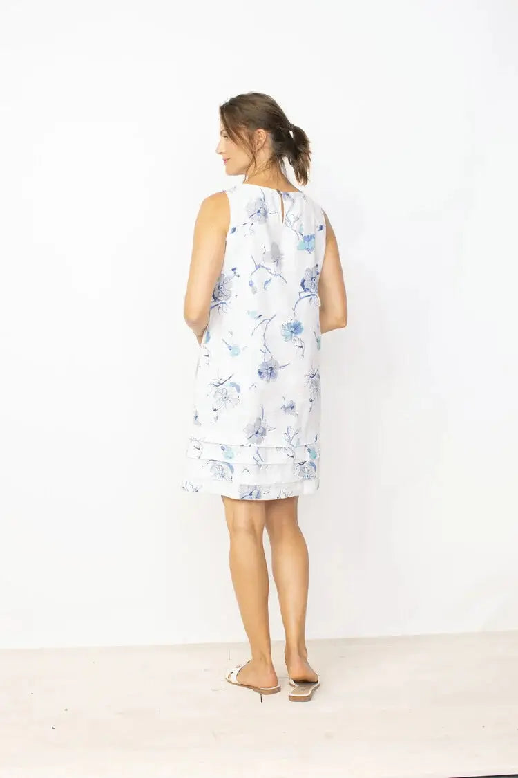 A woman in a Habitat high-quality Pleated Floral Hem Linen Dress, posing with one hand near her face.