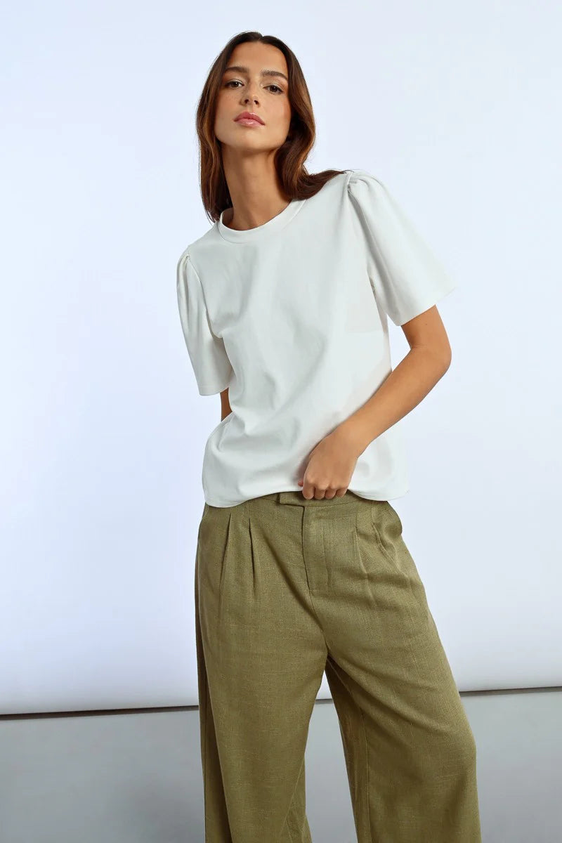 A person in a trendy Molly Bracken Back Heart Tee and olive green pants stands against a plain background.