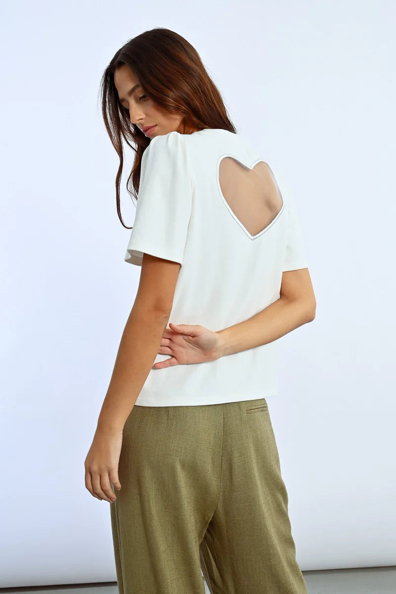 A person in a trendy Molly Bracken Back Heart Tee and olive green pants stands against a plain background.