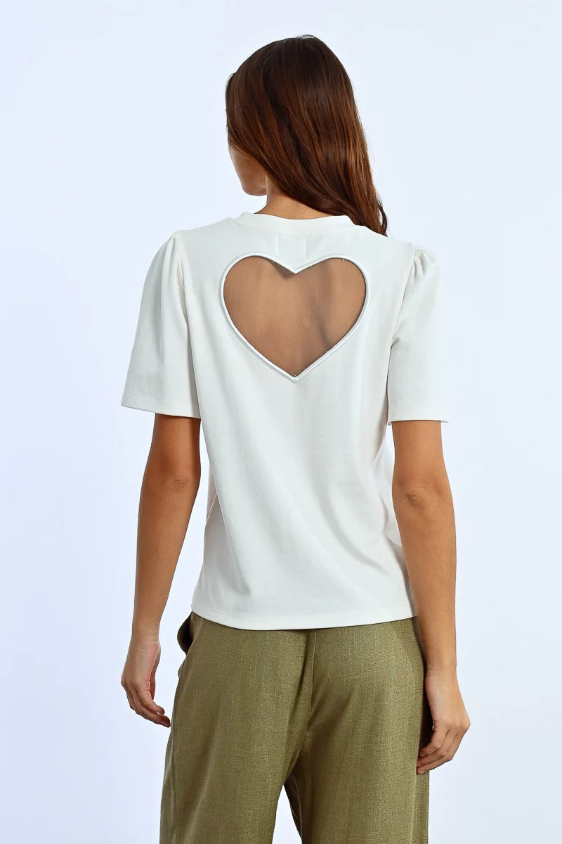 A person in a trendy Molly Bracken Back Heart Tee and olive green pants stands against a plain background.