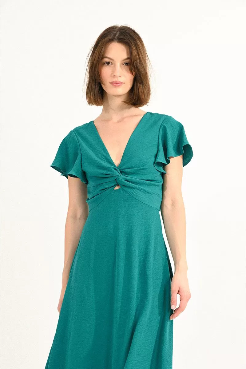 Woman posing in a stylish green Molly Bracken Long Cross-Bust Dress with capped sleeves and strappy sandals.