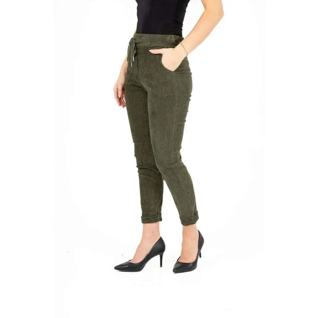 An individual dressed in a black strapless top, M Made In Italy's Olive Branch Woven Pant featuring pockets, and black pointed shoes stands against a white background, exemplifying a comfortable style.