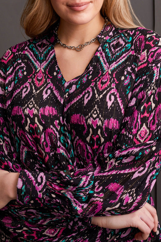 A person wearing Tribal's stylish Blouse with Faux Knot, showcasing pink, purple, and teal patterns, complemented by a silver necklace.