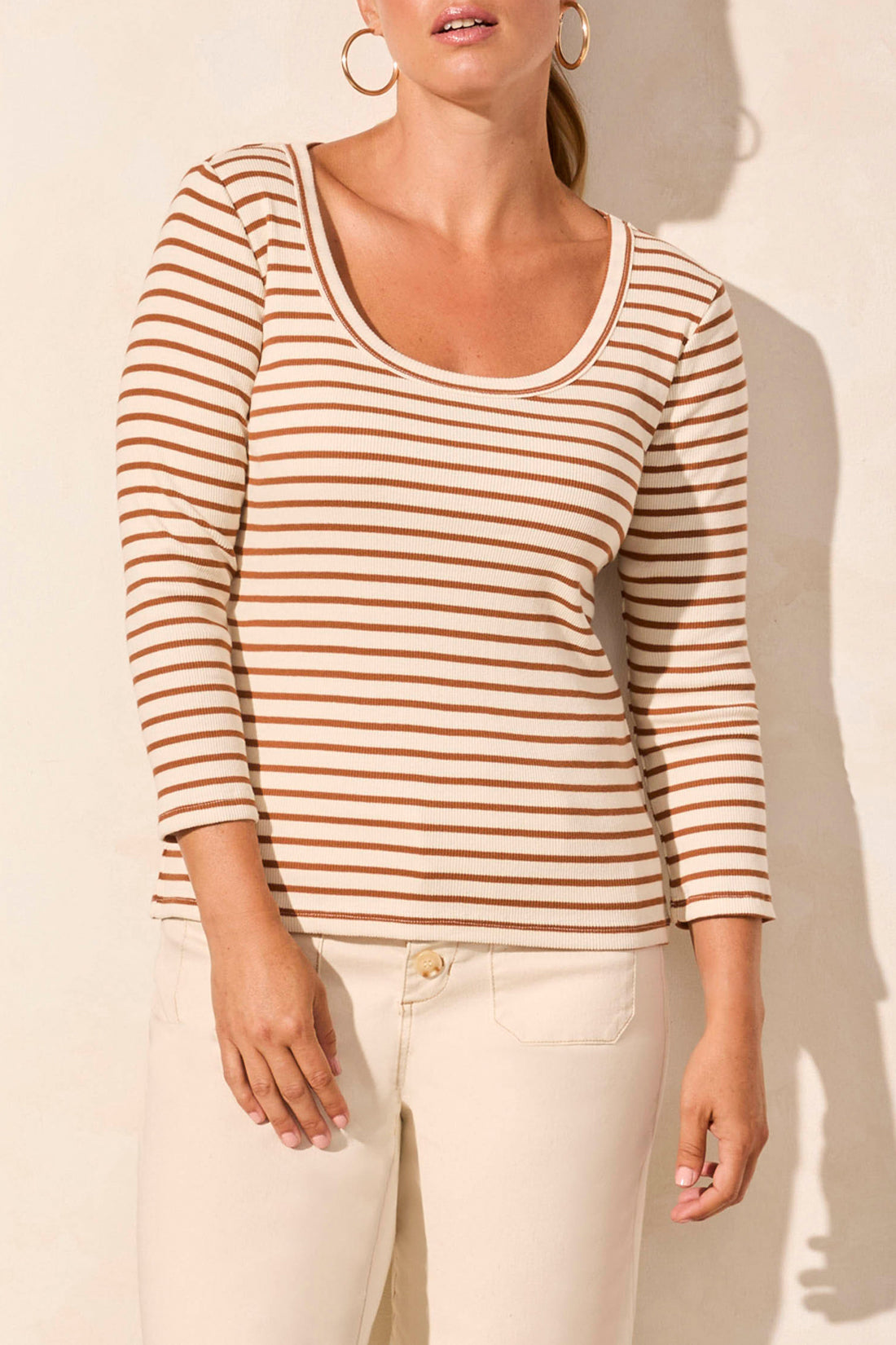 A person wearing a beige and brown 3/4 Sleeve Crew Neck Top by Tribal and cream pants stands against a light background.